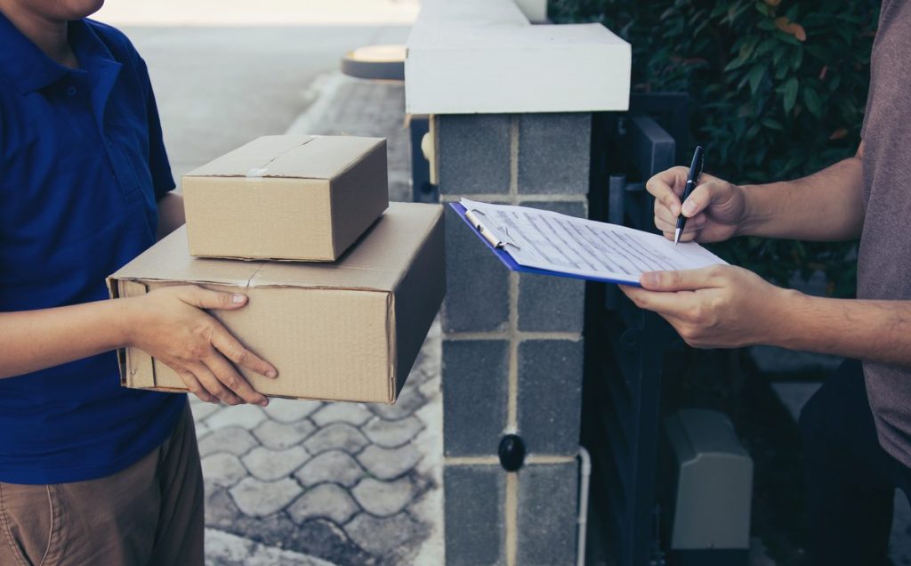 A courier handing over boxes with delivery paperwork